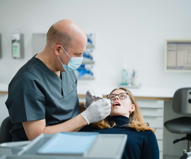 Behandler untersucht den Mundraum einer Patientin.