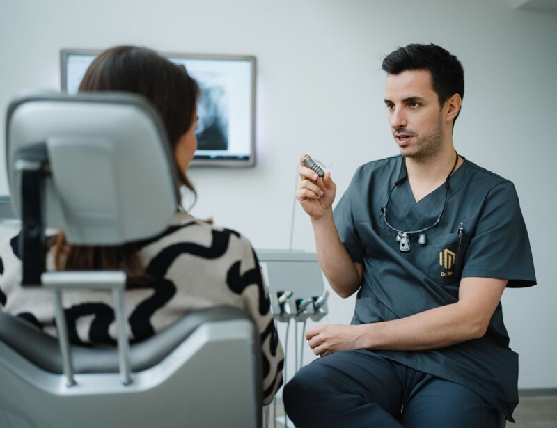 Dr. Mai zeigt Patientin ein Modell-Implantat.