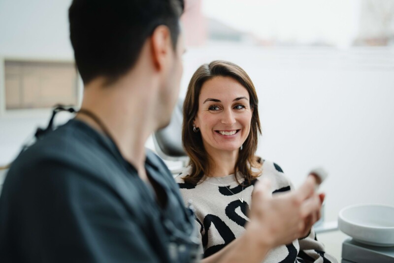 Zahnarzt kl&auml;rt Patientin &uuml;ber oralchirurgischen Eingriff in der Praxis in W&uuml;rzburg auf.