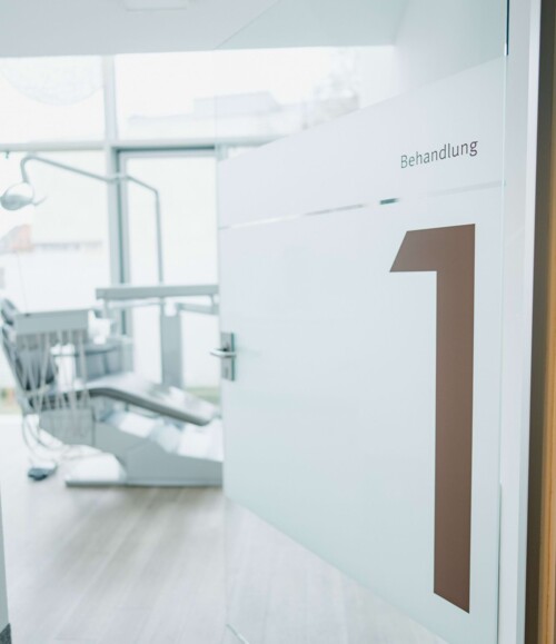 Detailsaufnahme der Praxisr&auml;umlichkeiten. Eine Glast&uuml;r steht offen und zeigt den Blick in einen Behandlungsraum