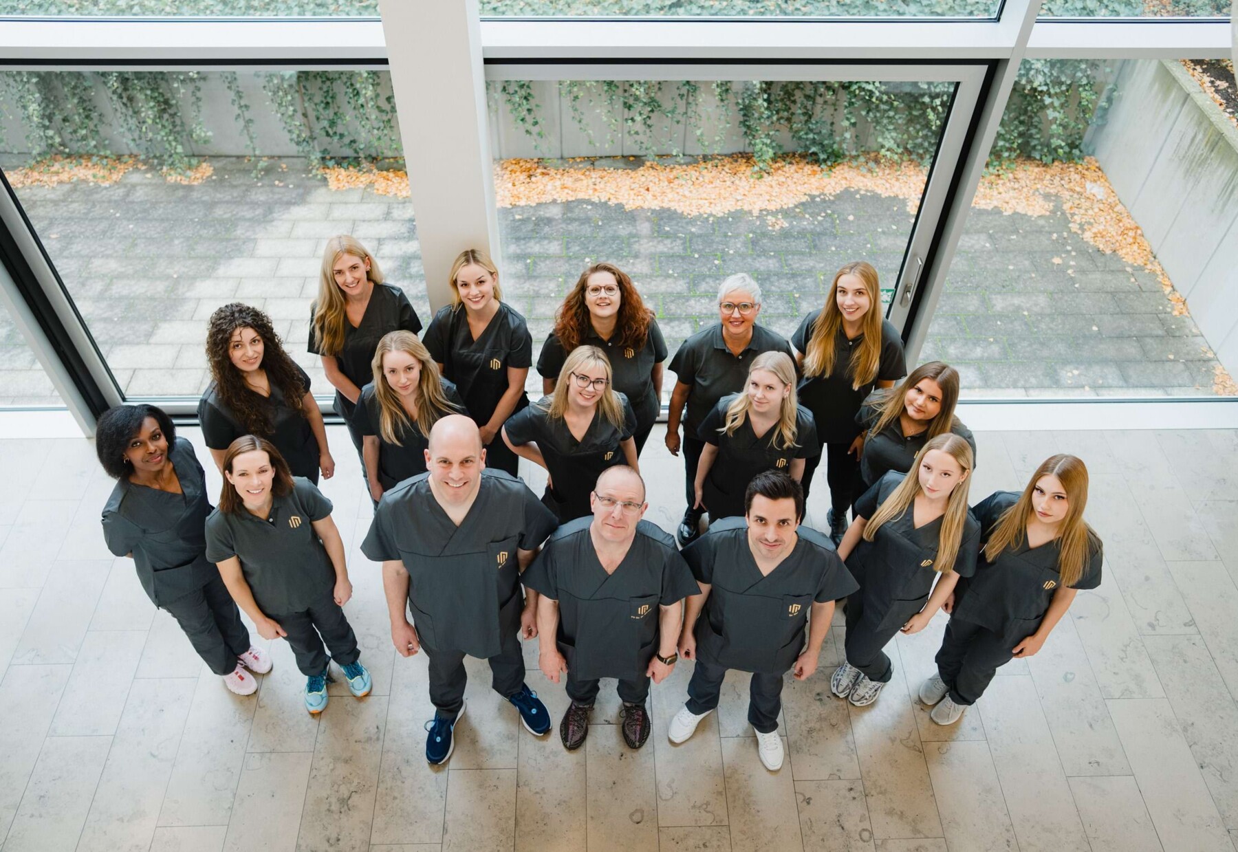 Aufnahme des gesamten Teams im Foyer der Praxisklinik &ndash; aufgenommen von einer Galerie von oben nach unten.