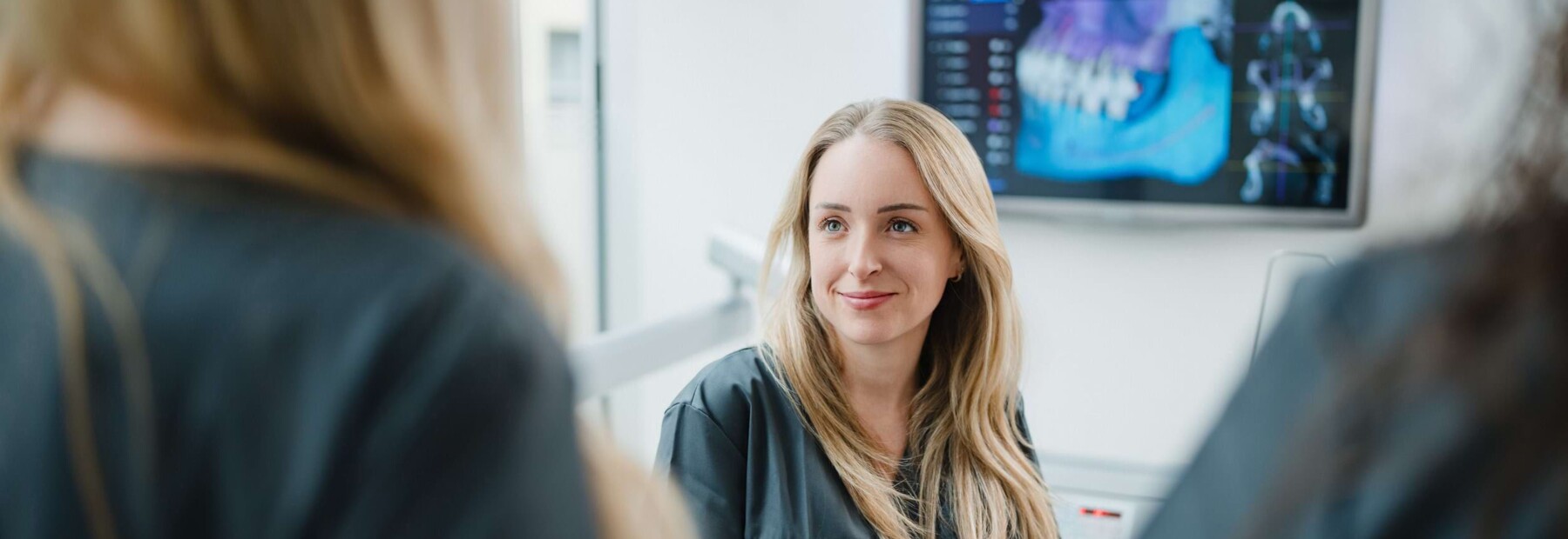 Eine junge Mitarbeiterin der Praxis unterh&auml;lt sich mit ihren Kolleginnen