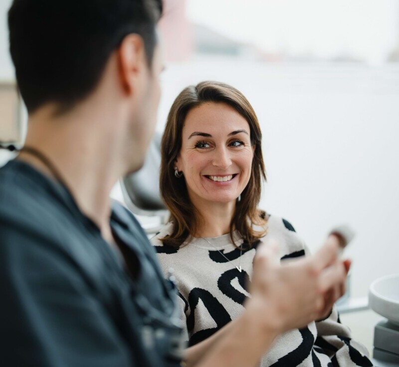 Zahnarzt spricht mit der Patientin &uuml;ber den Vorgang beim Weisheitsz&auml;hne entfernen in W&uuml;rzburg.