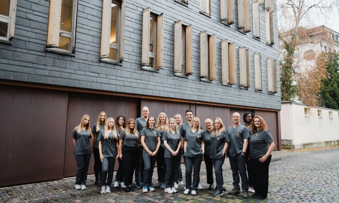 Gruppenfoto des gesamten Teams vor dem Geb&auml;ude der Praxisklinik