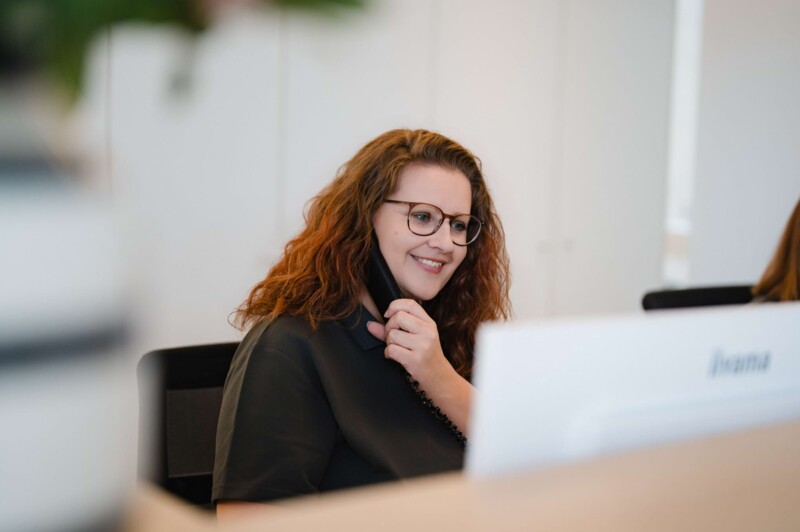 Eine freundliche Mitarbeiterin des Empfangs w&auml;hrend sie am Telefonieren ist.