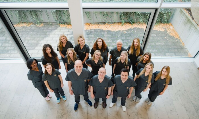 Foto des gesamten Teams, von oben nach unten fotografiert im Foyer der Praxisklinik