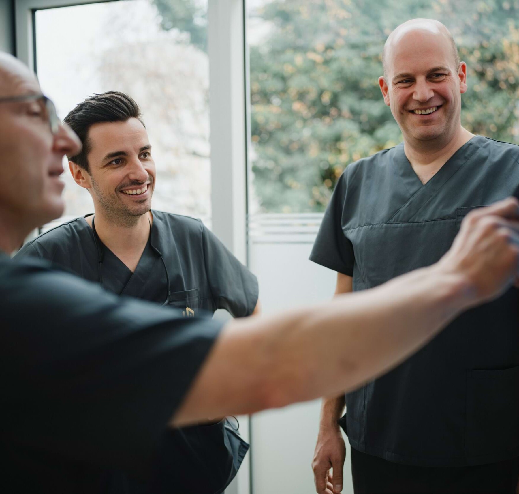Die Fach&auml;rzte Dr. Alexander Mai und Florian Will stehen in einem Behandlungszimmer und sehen auf ein R&ouml;ntgenbild