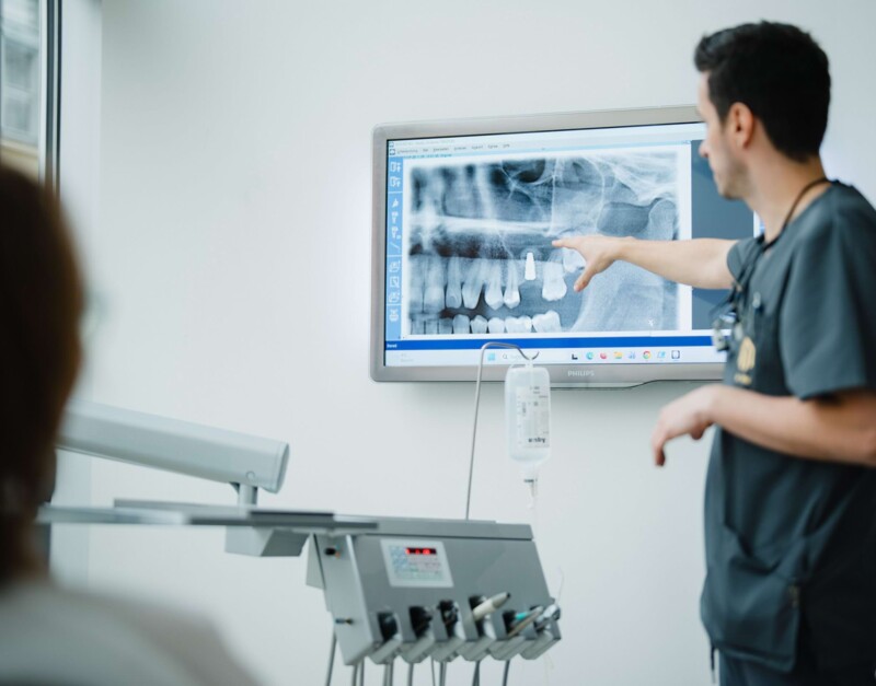 Dr. med. Mai deutet in der Praxis f&uuml;r Kieferchirurgie bei Kitzingen auf ein R&ouml;ntgenbild.